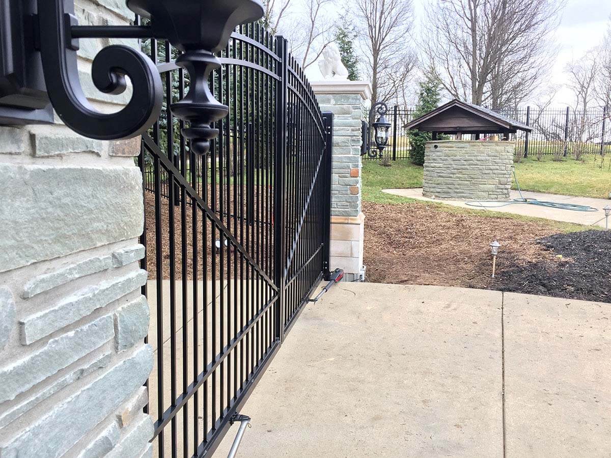 Ornate aluminum double swing gate with stone columns as entry to a home in Western PA