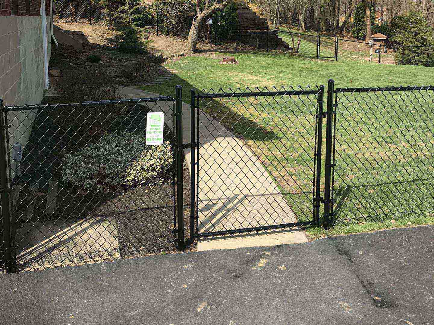 Black chain link fence with gate installed on a residential property