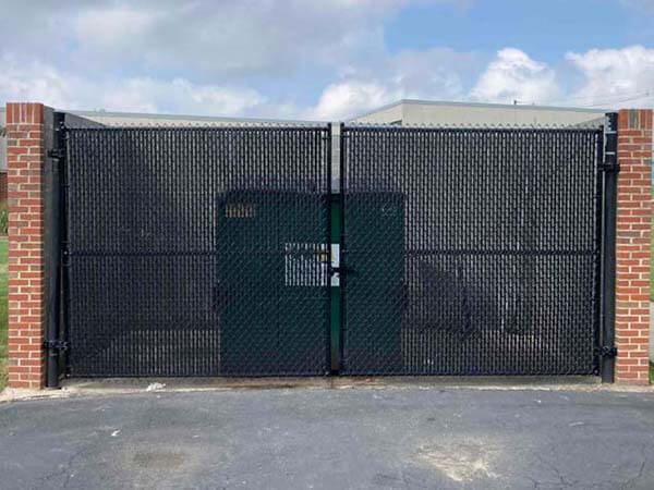 Black chain link fence with privacy slats as a dumpster enclosure for a commercial property in Butle