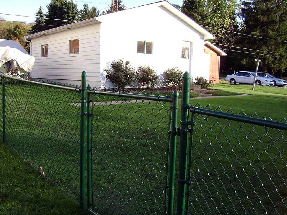 Green chain link fence with a gate installed around a residential home in Western Pennsylvania