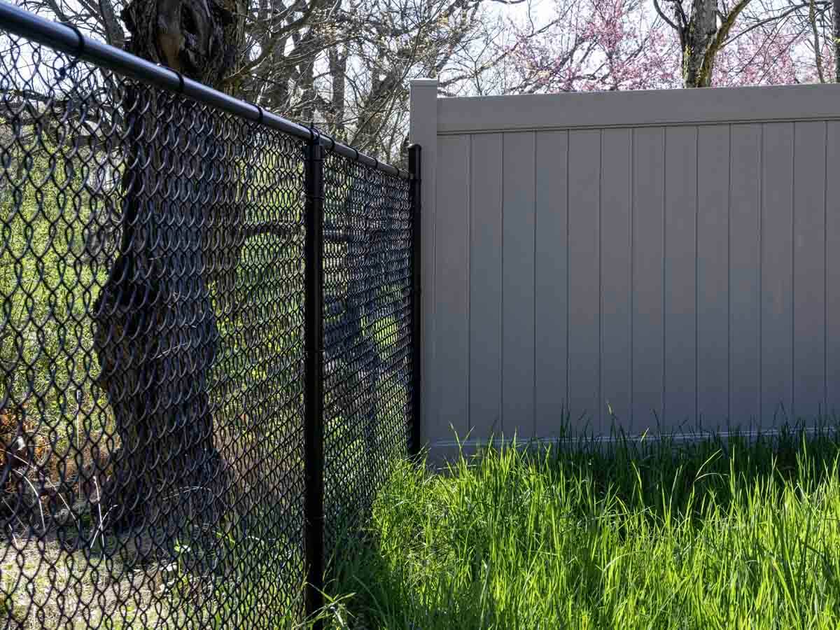 Black chain link fence installed up to a vinyl fence in Western Pennsylvania