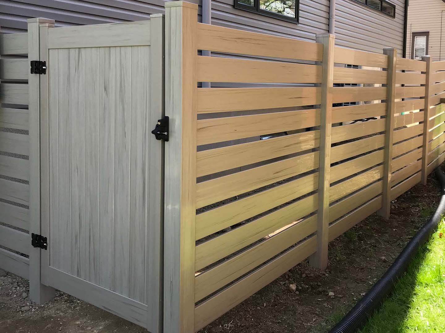 Wood grain horizontal vinyl fence installed around a residential property in Butler Pennsylvania