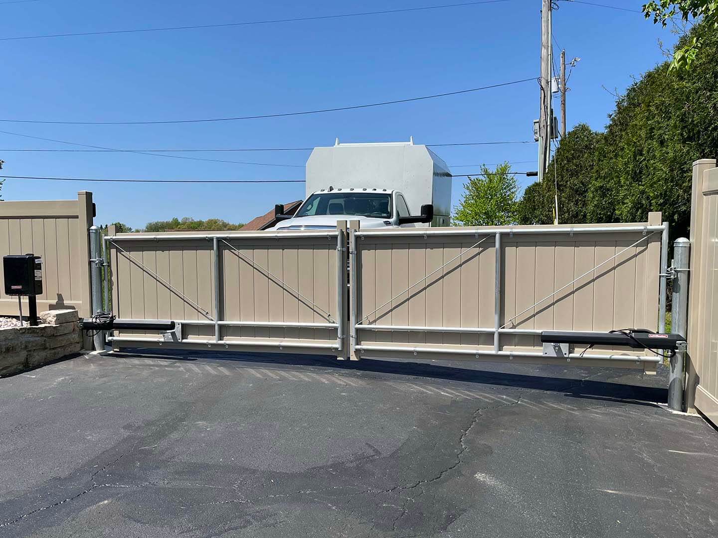 Brown dual-swing privacy gate with an automatic gate opener system installed on a commercial propert
