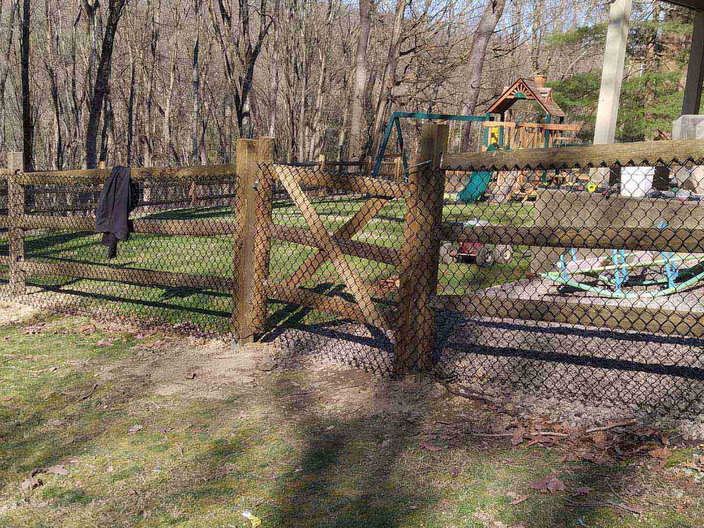 Post and board wood fence with wire mesh installed around a playground in Butler Pennsylvania